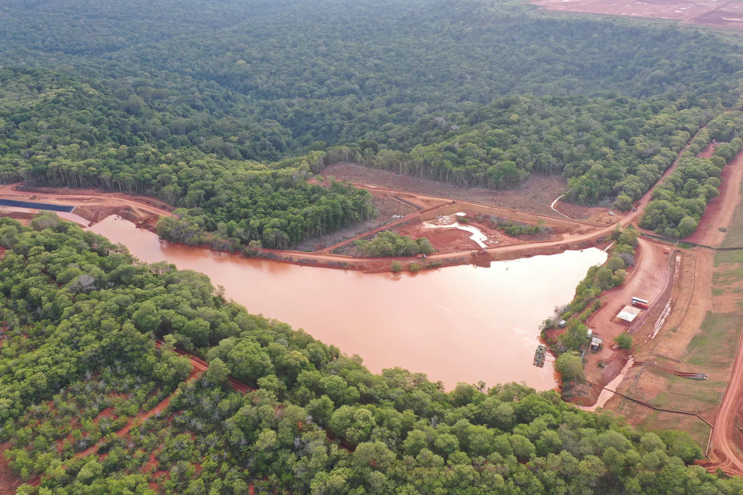 Lagoa de água avermelhada cercada por floresta, vista do alto