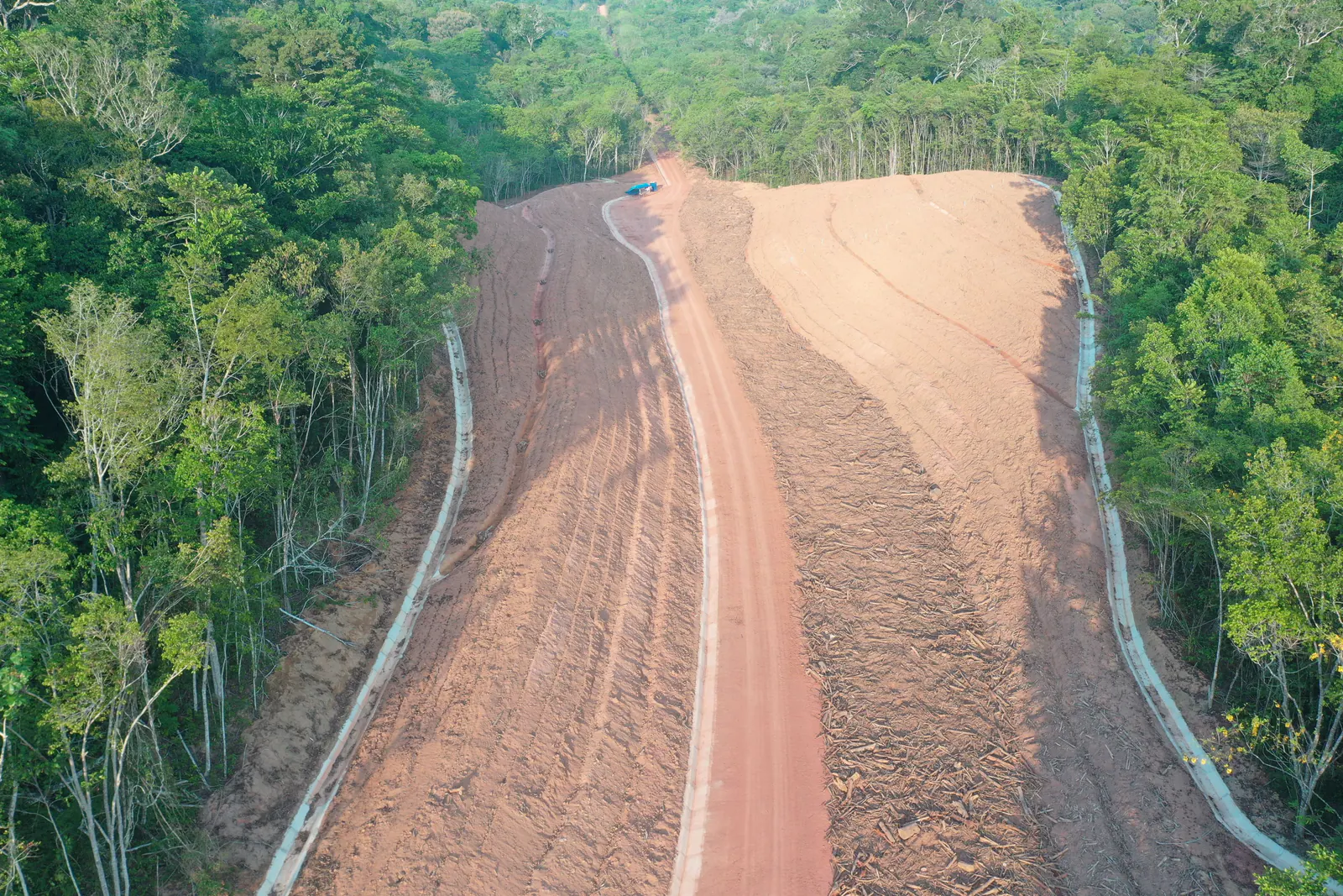 Vista aérea de talude conformado em faixa aberta na floresta, com canaletas nas bordas